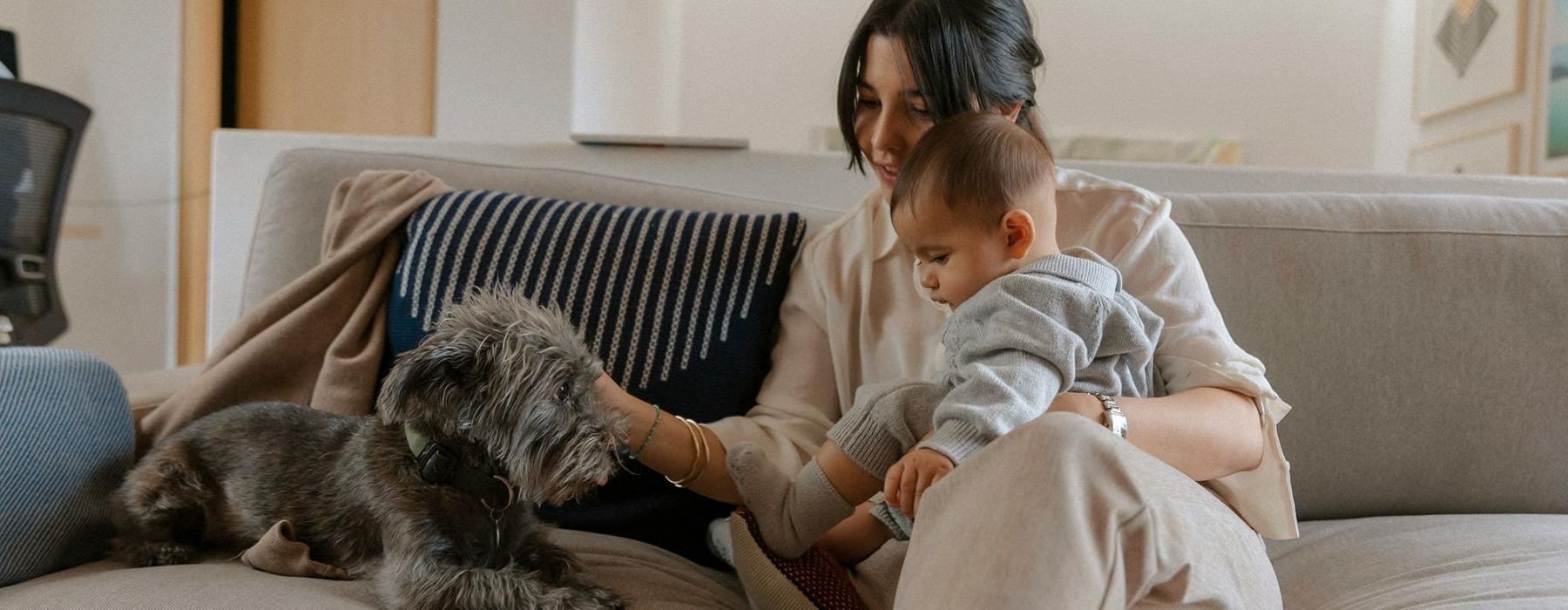 A woman and a baby on a couch with a dog